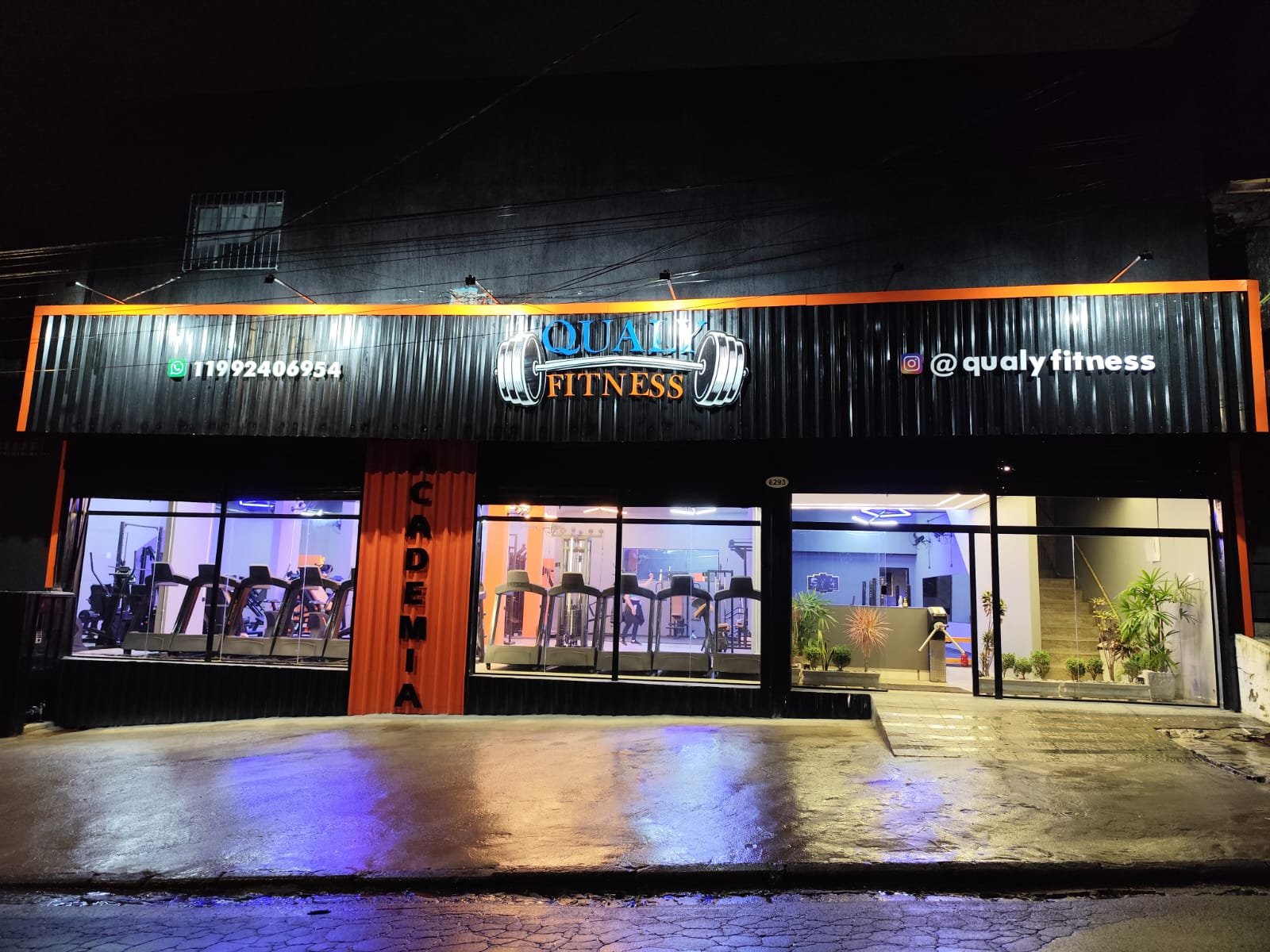 Fachada iluminada da Qualy Fitness à noite